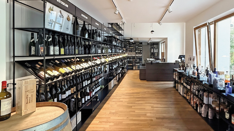 Moderner Weinhandel mit großflächiger Regalpräsentation, Holzfußboden und klar strukturierter Verkaufsfläche.