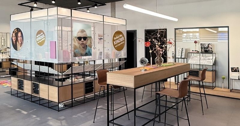 Modular optical interior with room divider, consultation table and integrated children’s area.