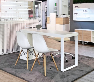 Moderner Beratungsbereich im Optikgeschäft mit Tisch, Sitzplätzen, Spiegel und Brillenpräsentation.