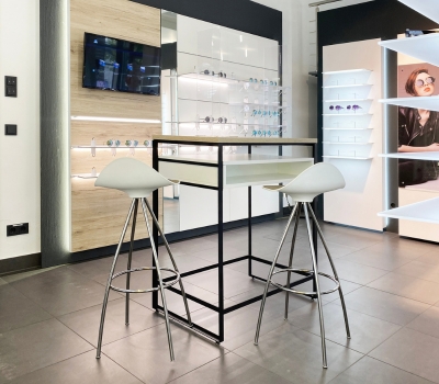 Stehberatung im Optikgeschäft mit Beratungstisch, Barhockern und modularer Brillenpräsentation.